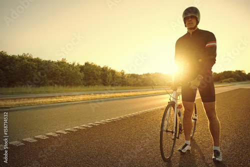 An athlete with bicycle on empty road