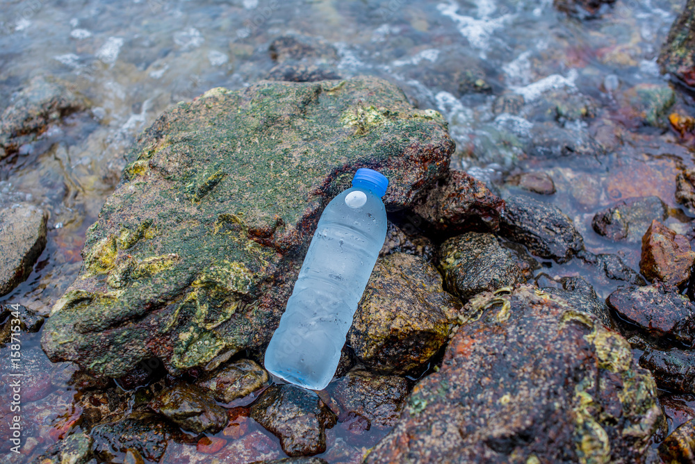 Selective focus cold drinking water in transparent bottles on sandy beach by the sea. Selective focus cold drinking water in transparent bottles on sandy beach by the sea.
