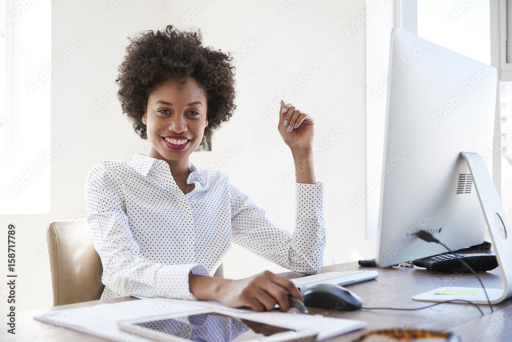Young black woman in an office smiling to camera, close up Young black woman in an office smiling to camera, close up
