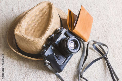 travel concept, straw hat/boater with black vintage camera and brown wallet