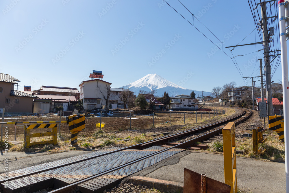 Fuji mountain with blue sky and train railway pass through city