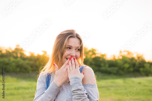Surprised young woman covering her mouth with hands outdoors