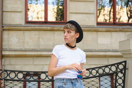 Close up portrait of female hipster with natural makeup and short haircut enjoying leisure time outdoors photo