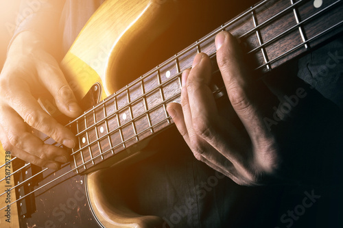 Live rock music background, electric bass guitar over bright blurred stage lights, close up