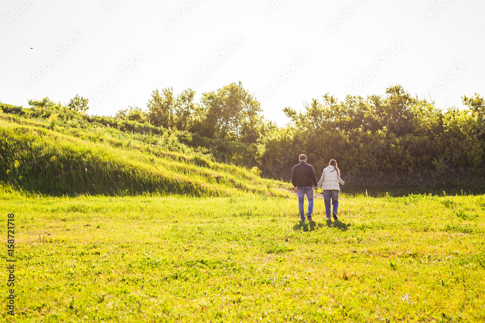 Man and woman holding hands and walking on nature, back view Man and woman holding hands and walking on nature, back view