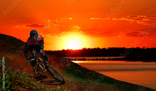 Young man riding a mountain bike at sunset