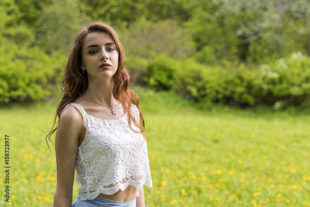 Portrait of a girl with long hair against the background of grass and trees Portrait of a girl with long hair against the background of grass and trees