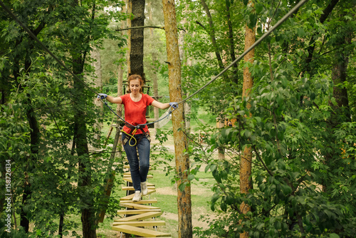 Woman climbing in forest adventure rope park