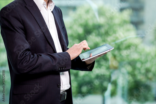 Close up image of business man holding a digital tablet,Portrait of handsome young man working with tablet in the office.Intelligent and confidents businessman holding touch pad with infographics