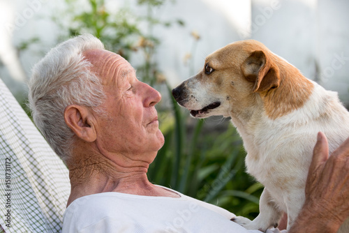 Old man and cute dog kissing