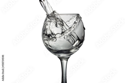 Water pours into a glass on a white background, monochrome image