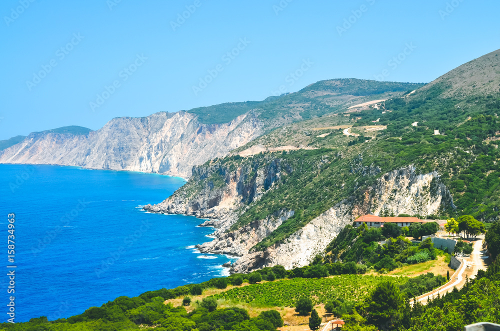 Cephalonia shore cliffs and blue coastal sea waters. Olive plantage in foreground