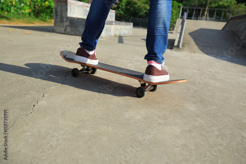 Fototapeta Naklejka Na Ścianę i Meble -  young skateboarder legs riding skateboard at skatepark