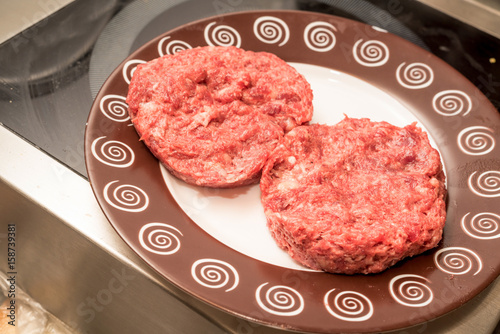 Fresh raw beef burger patties on plate photo