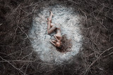 Beautiful naked woman lying on dry crack ground in fetal position. Top View