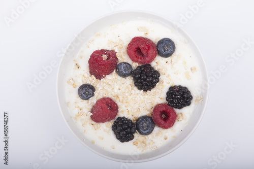 bowl of white yogurt with berries and oat flakes isolated