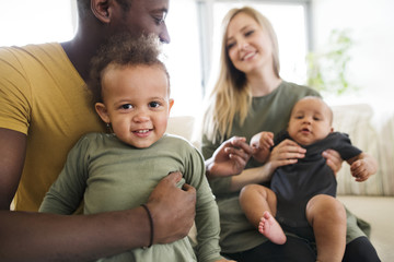 Young interracial family with little children at home.