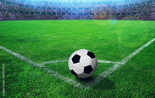 Soccer ball on grass in stadium illuminated bright spotlights.