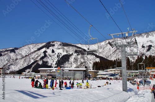 快晴のスキー場のリフトに乗る人たち