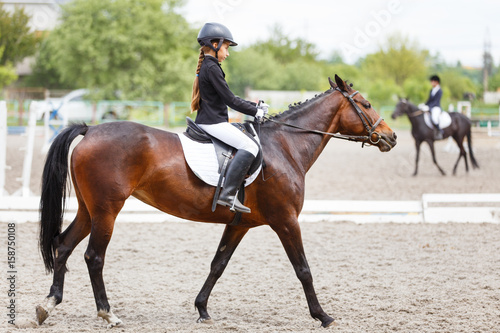 Young teenage girl in helmet riding horse on dressage equestrian competition © skumer