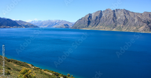 very blue lake with tall lakeside hills in the horizon