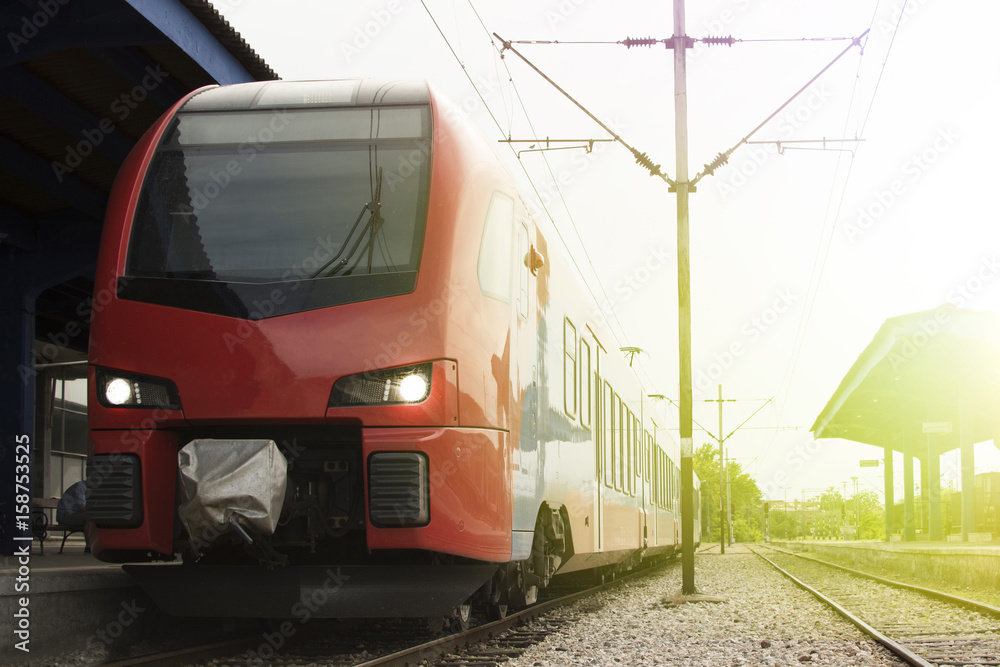 Naklejka premium Modern high-speed train on a clear day with motion blur. Beautiful railway station with modern red commuter train.