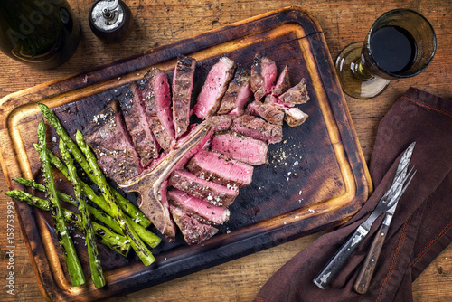 Barbecue dry aged Wagyu Porterhouse Steak sliced with green Asparagus on a cutting board