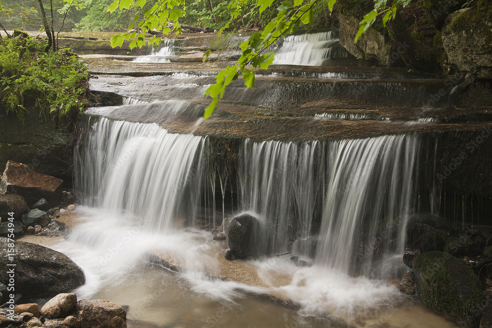 Obraz premium Beautiful waterfalls on golden rocks surrounded by moss on boulders.