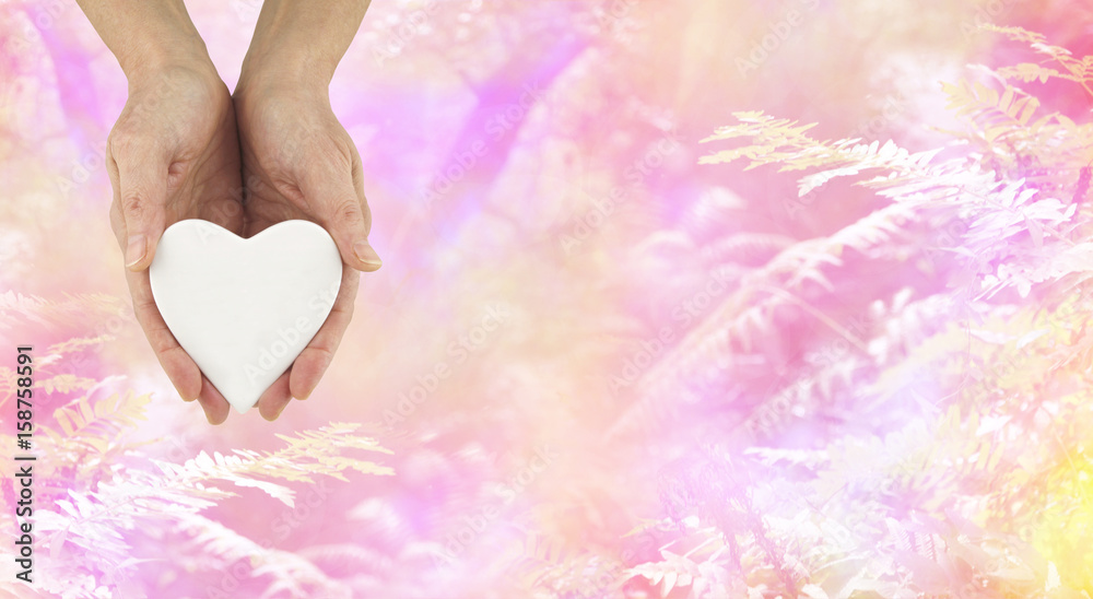 Love Nature - female hands holding a white ceramic heart shaped plaque against a beautiful pink fern and trees background with copy space