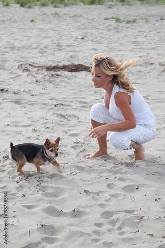 Beautiful blonde woman plays with her dog on the beach © Rusty