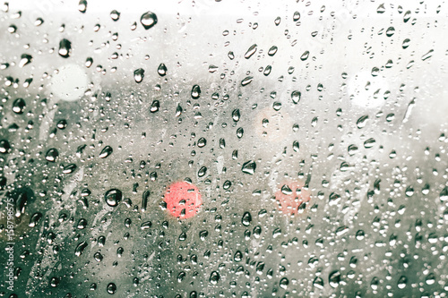 focusing on the rain droplets, tailights out of focus,Rainy night traffic ,lights in the raindrops on a car windscreen form a colorful background. photo