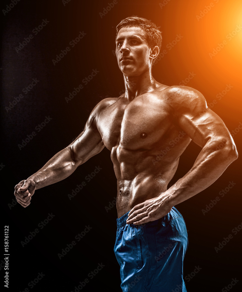 Fototapeta premium Muscular and fit young bodybuilder fitness male model posing ove