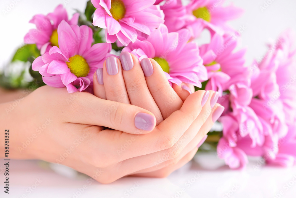 Hands of a woman with pink manicure on nails and pink flowers