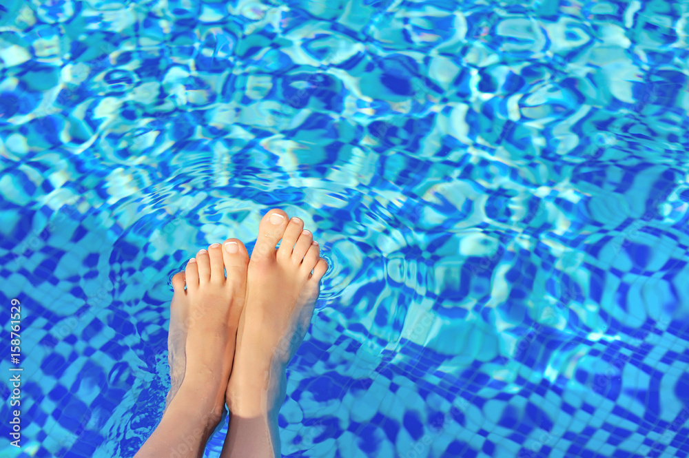Women's legs against a background of blue water pool