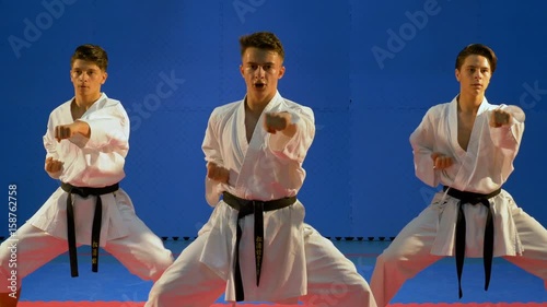Team of three students training and practicing karate punches in dojo