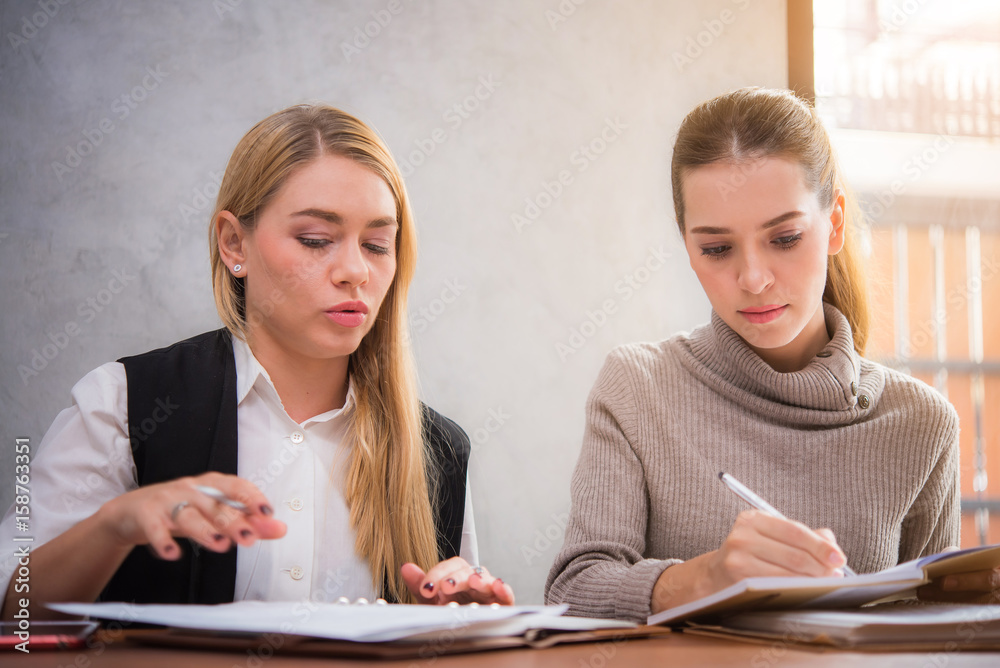 Two pretty women studying together in a library Two pretty women studying together in a library