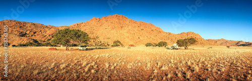 Camping in desert with pickup trucks and tents. Sunset evening.