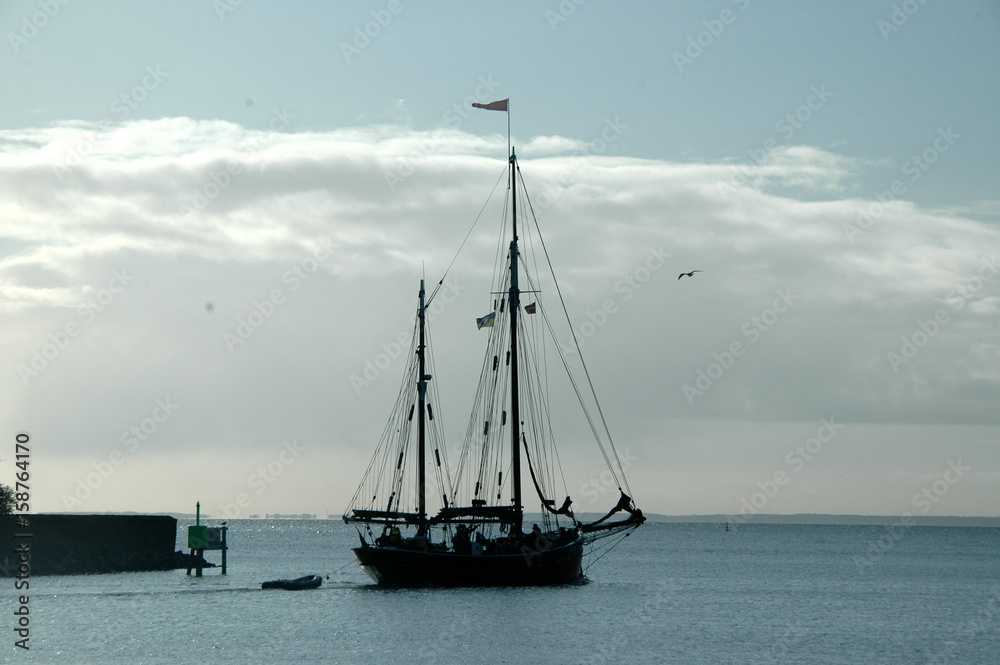 Silhouette of old sail ship leaving harbor.