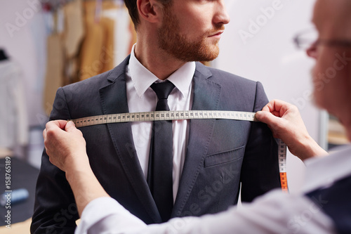 Fototapet Mid section portrait of tailor fitting bespoke suit to model