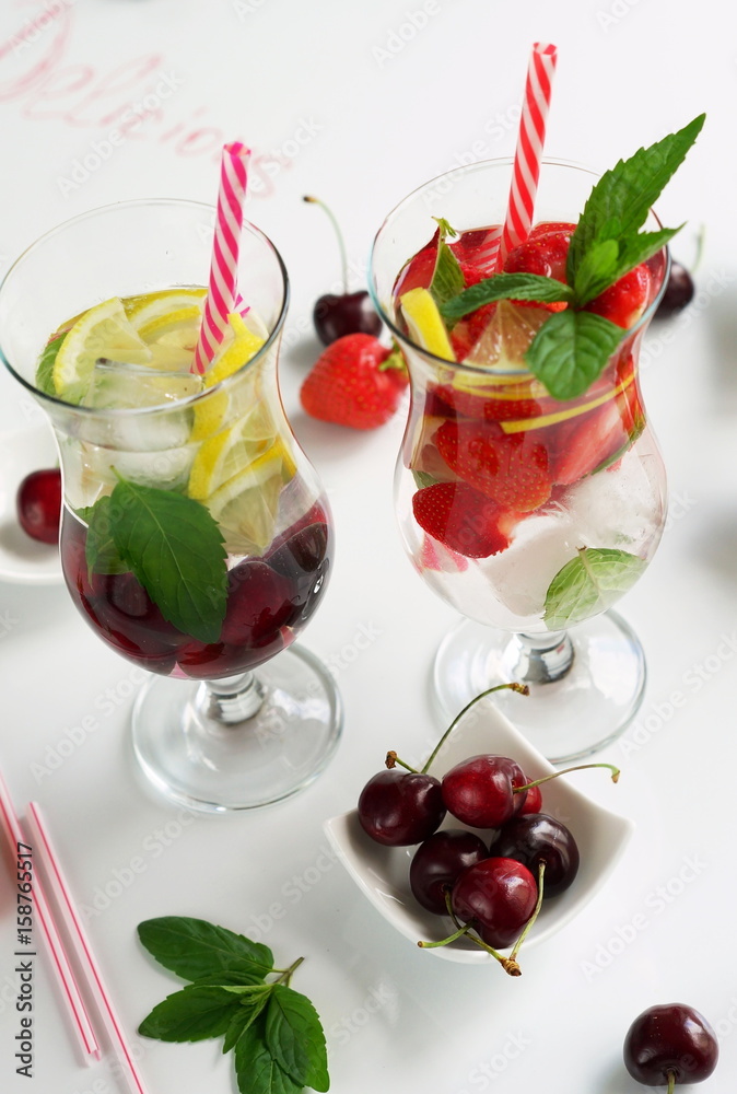 Detox water with strawberries, cherries, lemon and mint on white background Detox water with strawberries, cherries, lemon and mint on white background