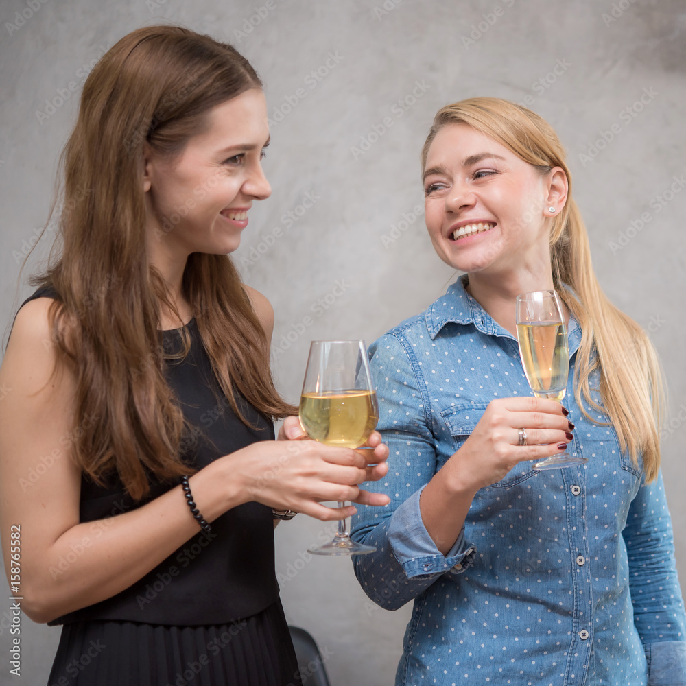 Two beautiful young women talking and smiling while drinking wine and champagne Two beautiful young women talking and smiling while drinking wine and champagne