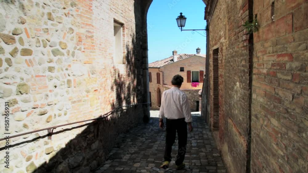 back of man in medieval village in Italy back of man in medieval village in Italy