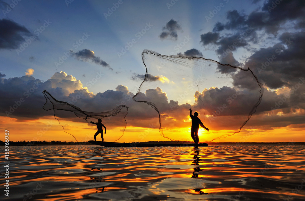 Silhouette fisherman trowing the nets on during sunset,during sunrise,Thailand