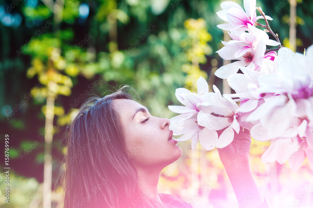 Fototapeta premium girl smelling pink, blossoming, magnolia flowers from tree