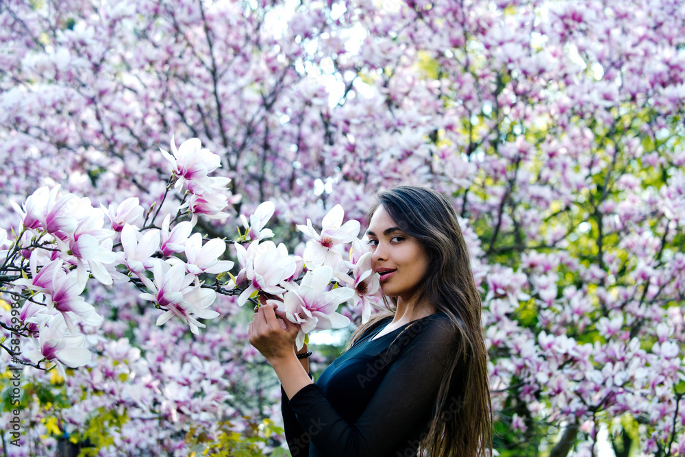woman with long, brunette hair posing at magnolia tree woman with long, brunette hair posing at magnolia tree