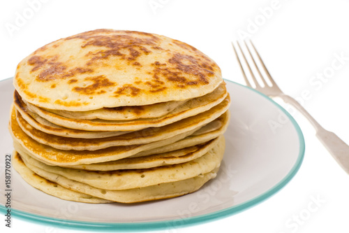 Stack of fried vanilla pancakes on plate on white background