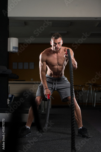 Young Man Battling Ropes At Gym Workout Exercise