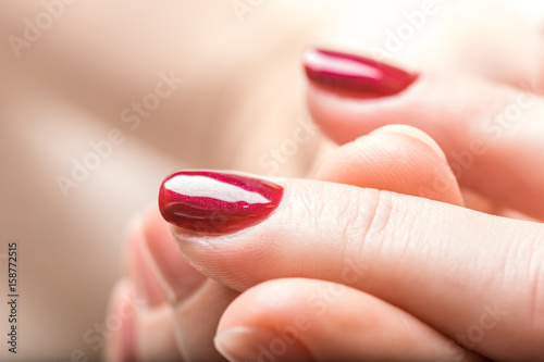 Manicure nail paint purple color. Elegant women's hands doing a manicure applying red nail polish.