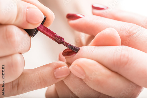 Manicure nail paint purple color. Elegant women s hands doing a manicure applying red nail polish.