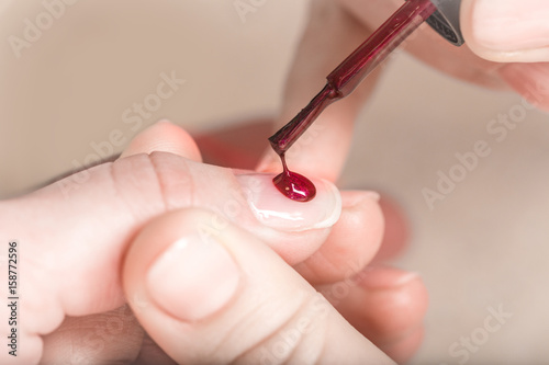 Manicure nail paint purple color. Elegant women s hands doing a manicure applying red nail polish.